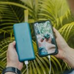 Hand holding a green portable power bank charging a smartphone, illustrating portable power banks explained