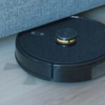 Black robot vacuum cleaner on a wooden floor, illustrating a robot vacuum buying comparison guide